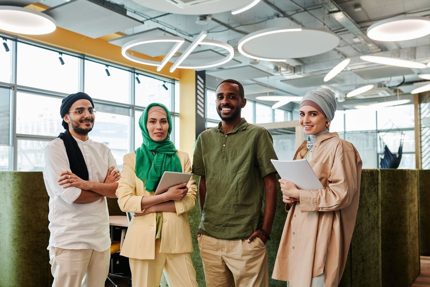 A smiling team of professionals stands together in a modern office.