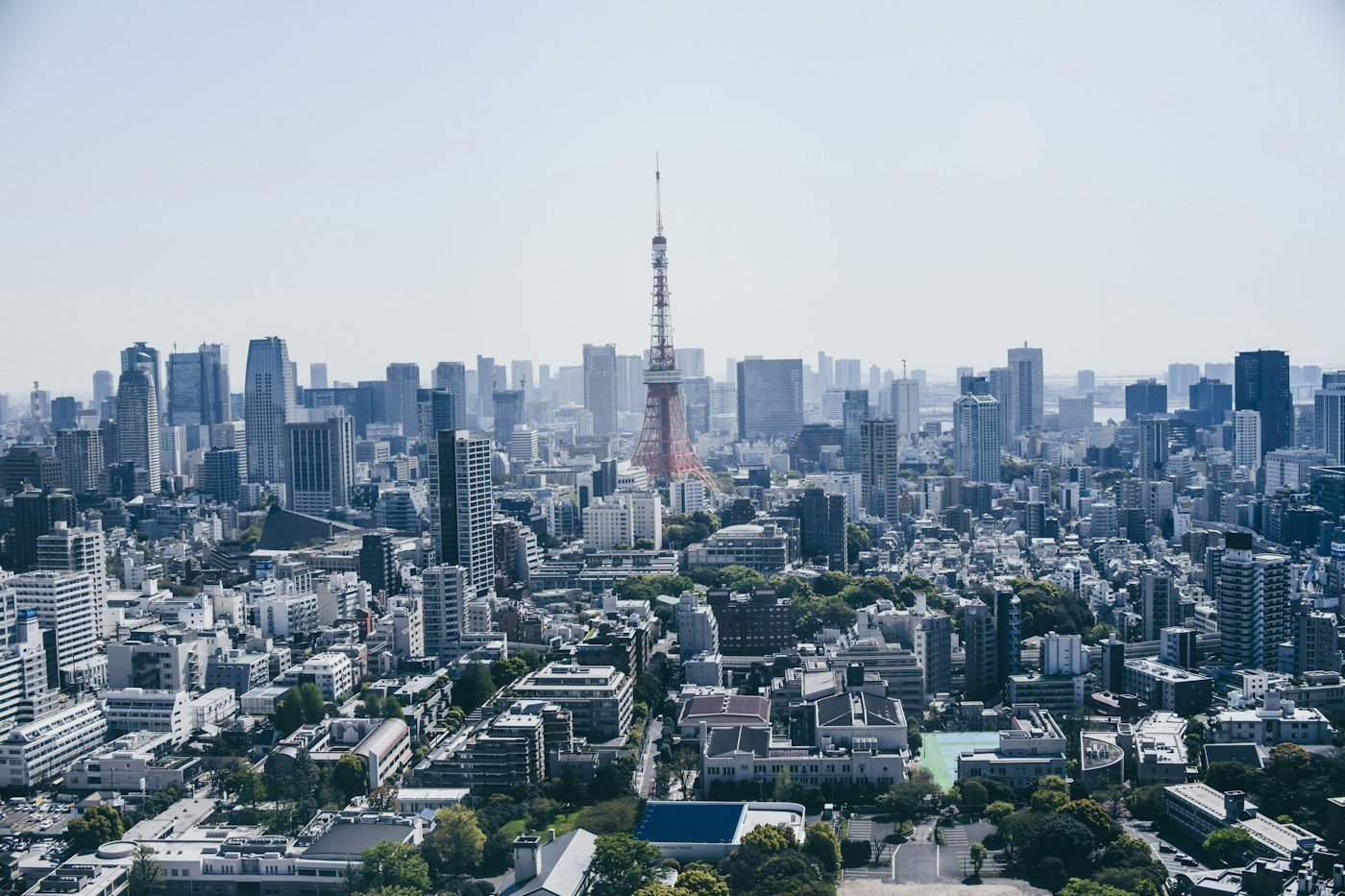 Tokyo Tower rising among city buildings under blue sky