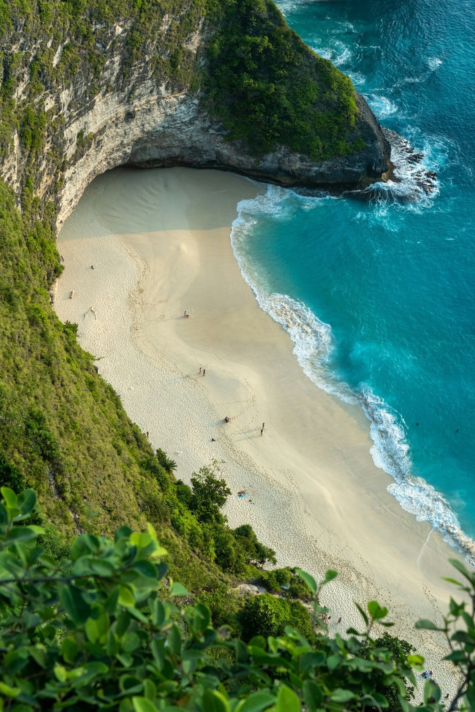 Bali cliffs enclosing a turquoise bay and white sand beach