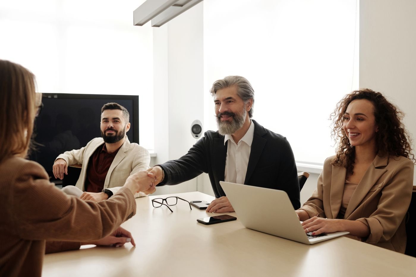 Professionals shake hands across an office meeting table.