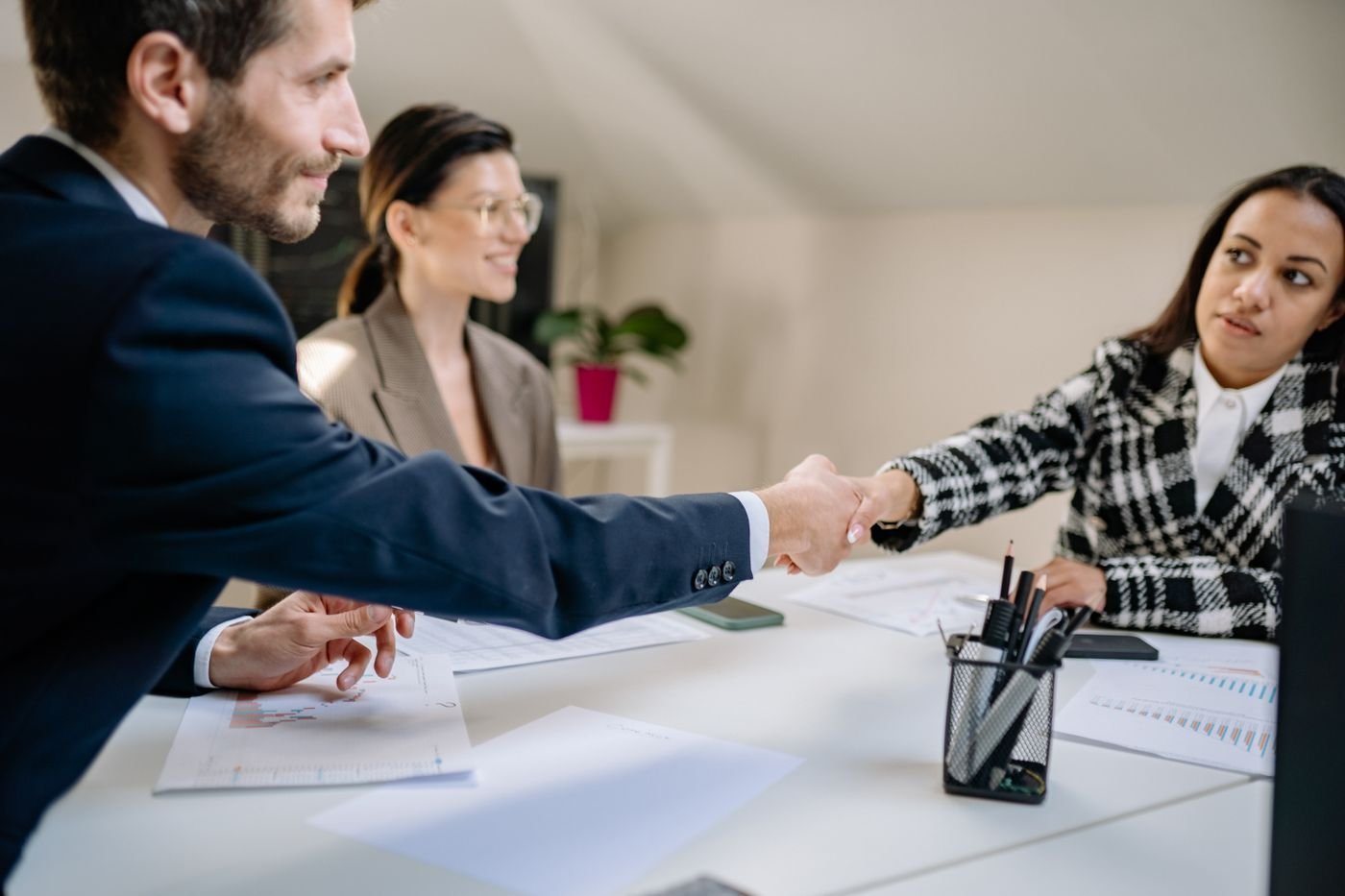 A diverse team concludes a meeting with a handshake.