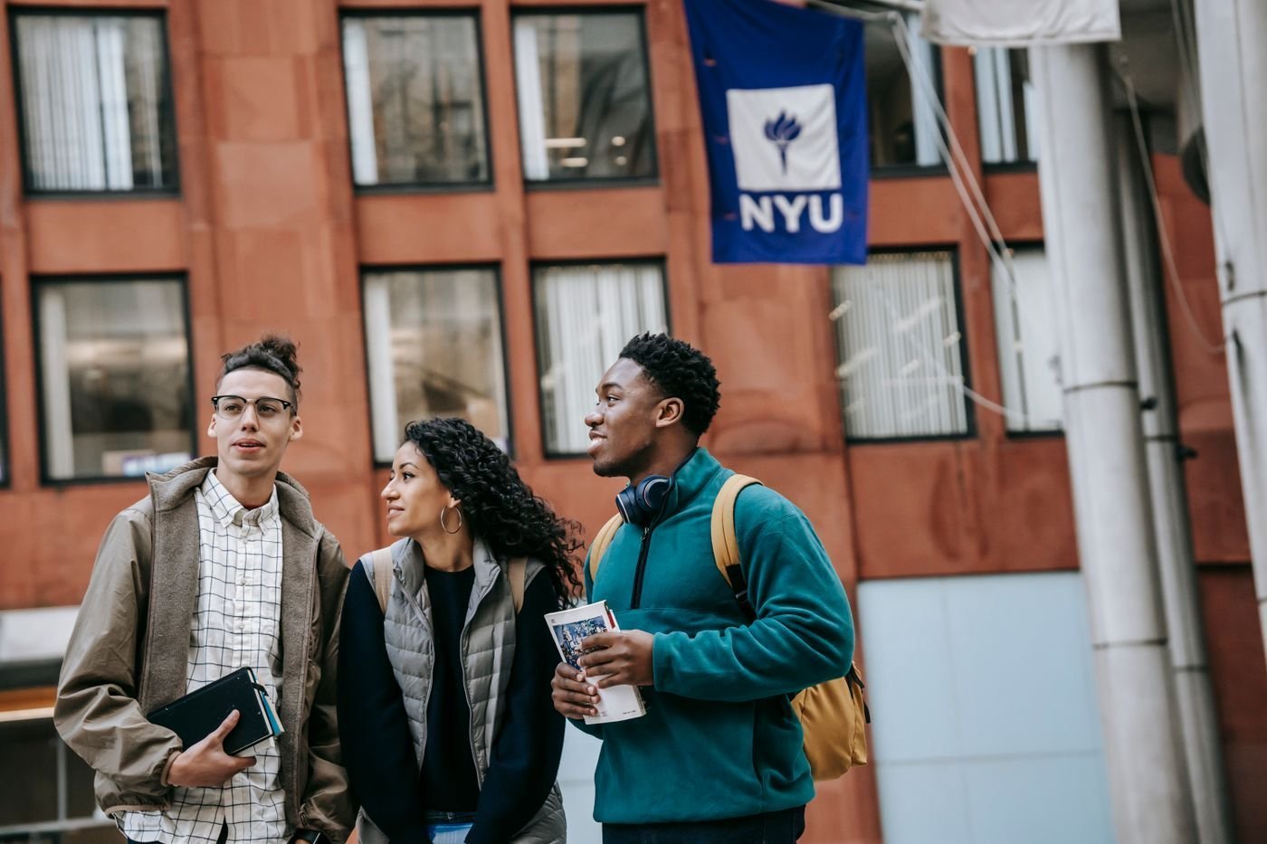 A smiling group of students stands together outside a university.