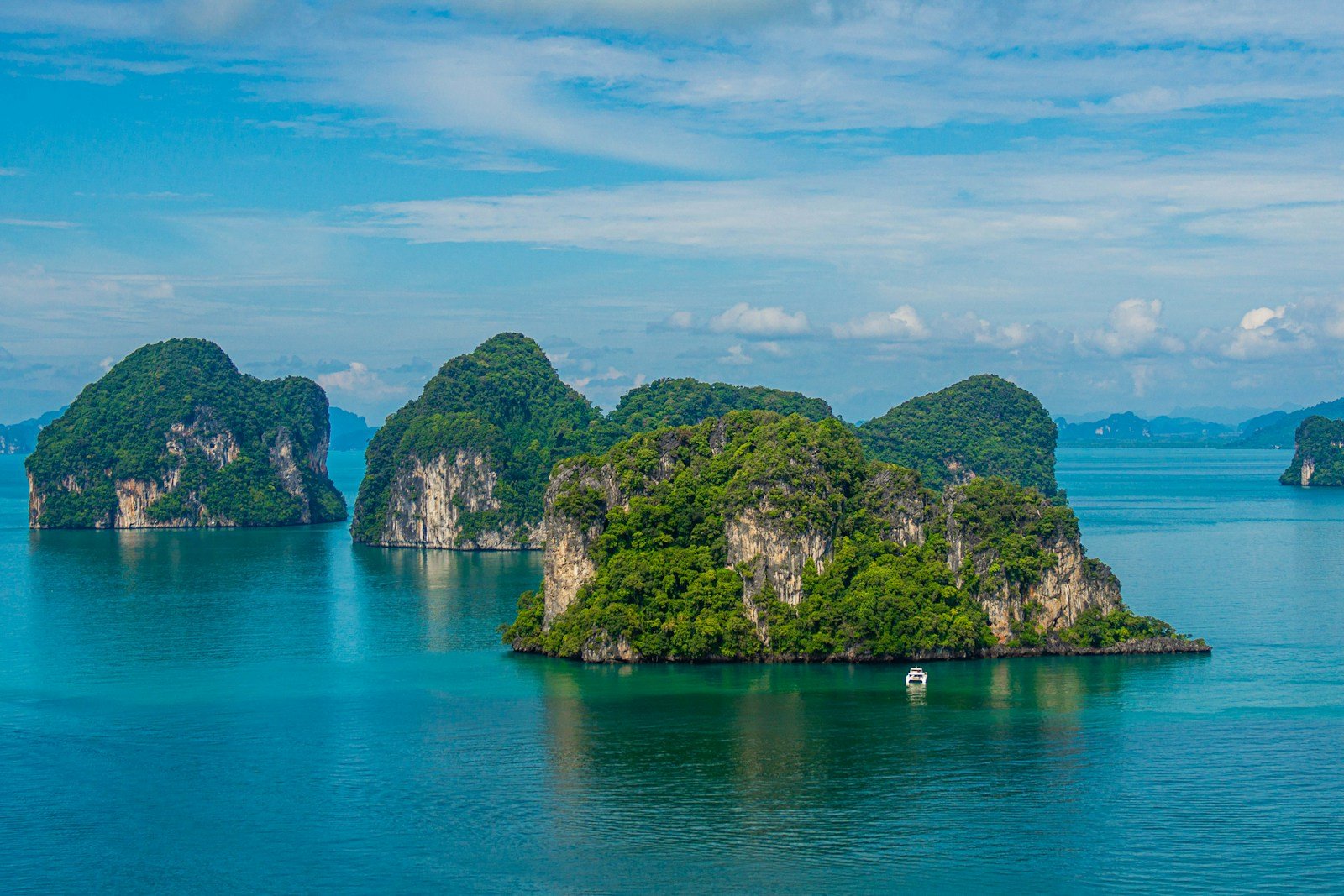 Forested limestone islands rising from turquoise Thai sea